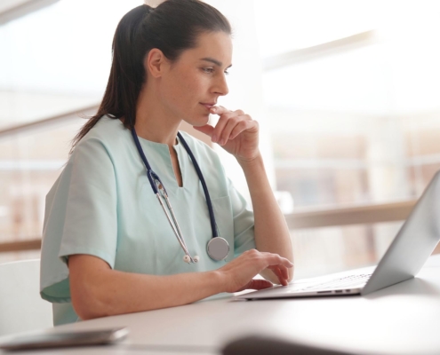 Nurse sitting in office looking at laptop