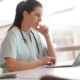 Nurse sitting in office looking at laptop