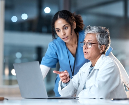 Two medical professionals looking at information on laptop